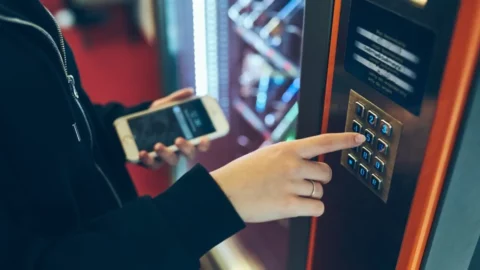 a woman makes a purchase at a vending machine